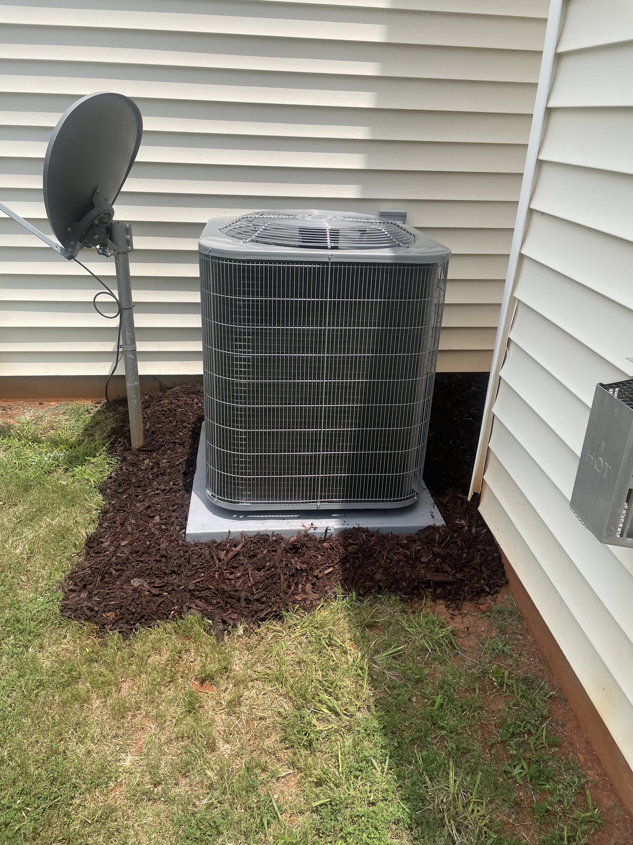 New outdoor condenser on a pad beside a house